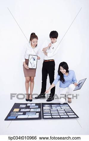 Stock Photograph - three interior designers working on a portfolio. Fotosearch
