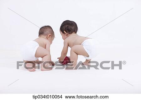 Picture - two babies in diaper with an apple. Fotosearch