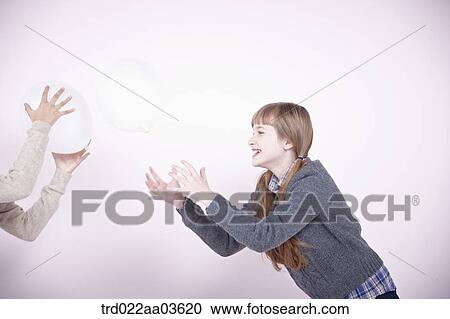 Stock Image - two girls playing with white balloons. Fotosearch