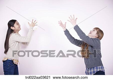 Stock Image - two girls playing with white balloons. Fotosearch