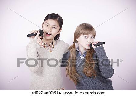 two girls singing a song with microphones View Large Photo Image Picture - two girls singing a song with microphones. Fotosearch