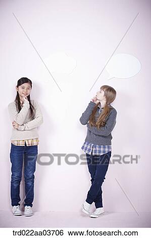 Stock Photograph - two girls standing together while one girl has speech bubble. Fotosearch