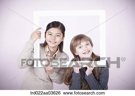 two girls with empty frame around themselves View Large Photo Image Stock Photograph - two girls with empty frame around themselves. Fotosearch