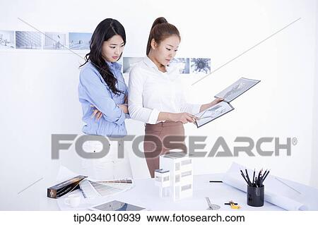 Stock Photo - two interior designers looking at pictures. Fotosearch