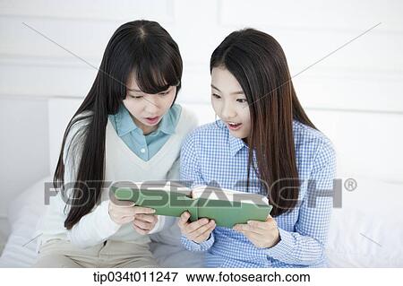Stock Photo - two ladies reading a book together. Fotosearch