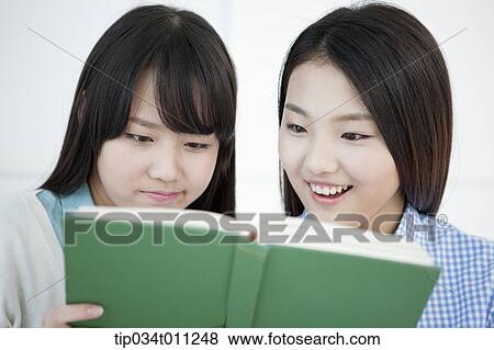 Stock Photo - two ladies reading a book together. Fotosearch