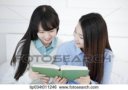Stock Photograph - two ladies reading a book together. Fotosearch