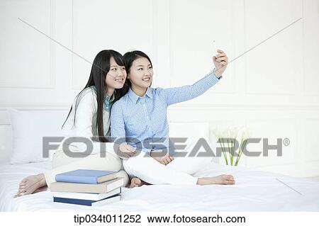 Stock Image - two ladies taking photo together. Fotosearch