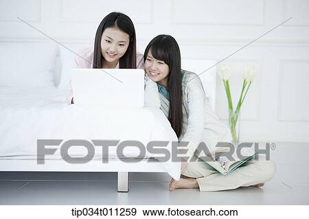 Stock Photo - two ladies using laptop together. Fotosearch