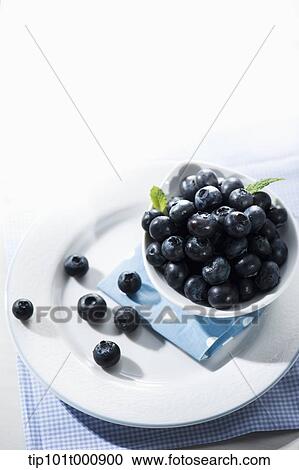 Stock Image - a bowl of blue berries on a plate. Fotosearch