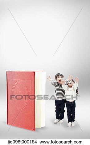 Picture - a boy and a girl next to a book . Fotosearch