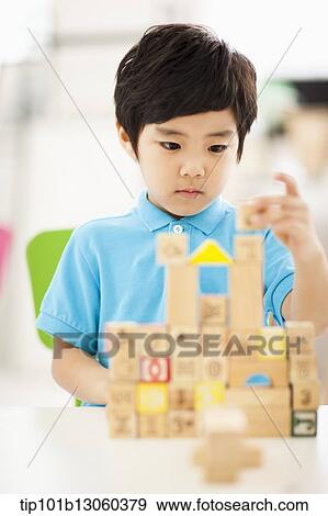 Stock Photo - a boy building a castle with wood cubes. Fotosearch