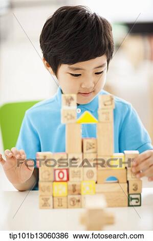 Stock Photograph - a boy building a castle with wood cubes. Fotosearch