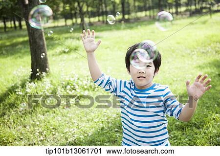 Stock Image - a boy chasing soap bubbles. Fotosearch