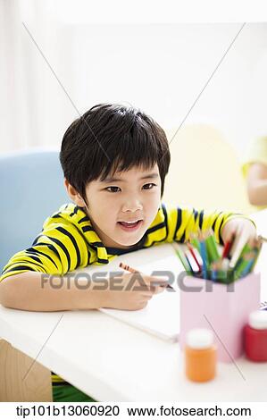 Stock Image - a boy drawing on a sketch book with crayon. Fotosearch