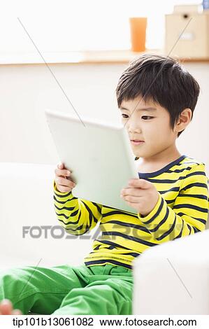 a boy playing with a tablet View Large Photo Image Stock Image - a boy playing with a tablet. Fotosearch