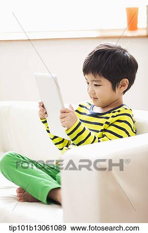 Stock Photo - a boy playing with a tablet. Fotosearch