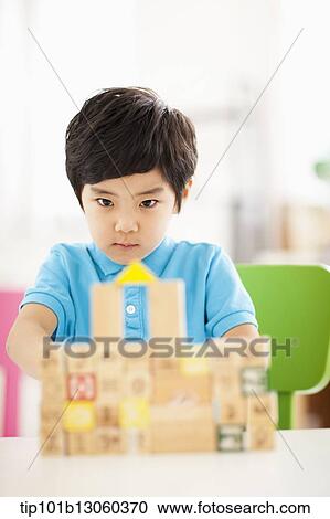 Stock Image - a boy playing with wood cubes with icons. Fotosearch