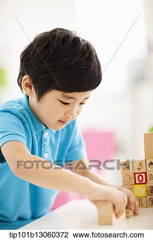 Stock Image - a boy playing with wood cubes with icons. Fotosearch