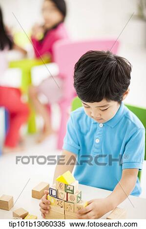 Stock Photography - a boy playing with wood cubes with icons. Fotosearch