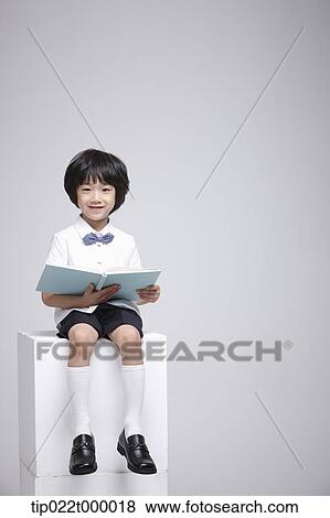 a boy sitting on a box reading a book View Large Photo Image Stock Photo - a boy sitting on a box reading a book. Fotosearch