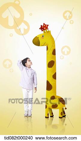 Stock Image - a boy standing next to a giraffe . Fotosearch