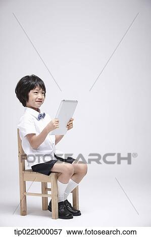 a boy using tablet PC on a chair View Large Photo Image Stock Photo - a boy using tablet PC on a chair. Fotosearch