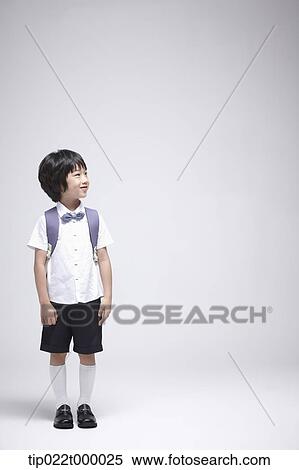 Stock Photography - a boy wearing a school bag standing in white background. Fotosearch