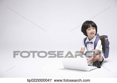 Stock Photo - a boy wearing a school bag using a laptop . Fotosearch