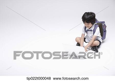 Stock Photo - a boy wearing a school bag using a laptop . Fotosearch