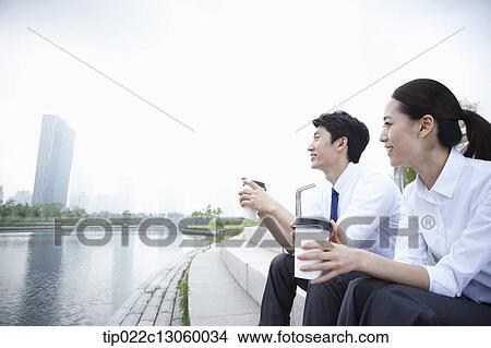 Picture - a business man and a business woman next to a river. Fotosearch