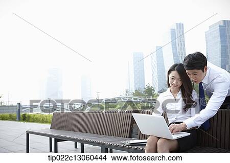 Picture - a business man and a business woman working together. Fotosearch