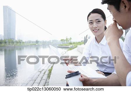 Stock Image - a business man and a business woman next to a river. Fotosearch