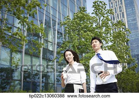 Stock Photo - a business man and a business woman walking on the street. Fotosearch