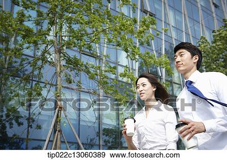 Stock Photo - a business man and a business woman walking on the street. Fotosearch