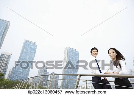 Stock Photo - a business man and a business woman leaning on a fence. Fotosearch