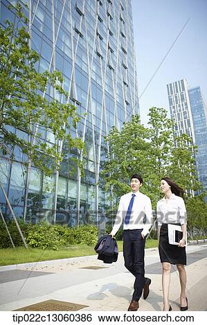 Stock Photograph - a business man and a business woman walking on the street. Fotosearch