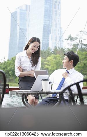 Stock Photography - a business man and a business woman talking to each other. Fotosearch