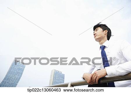 Stock Image - a business man leaning on a fence. Fotosearch