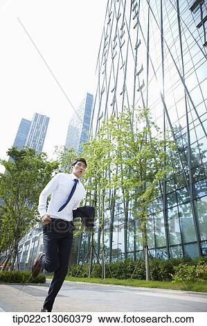 Stock Photo - a business man running on the street. Fotosearch