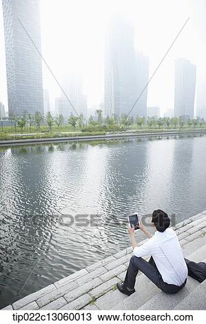 Stock Image - a business man sitting next to a river. Fotosearch