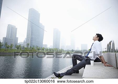 Stock Photograph - a business man sitting next to a river. Fotosearch