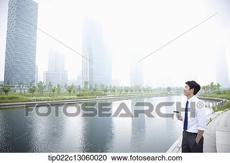 Stock Image - a business man standing next to a river. Fotosearch