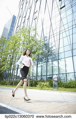 Stock Image - a business woman running with a coffee. Fotosearch