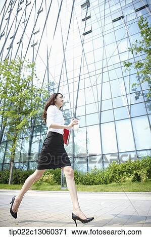 Stock Image - a business woman running with a coffee. Fotosearch
