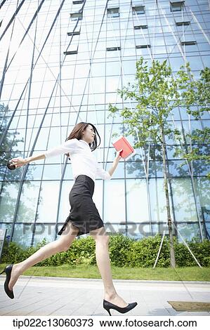 Stock Image - a business woman running with a coffee. Fotosearch