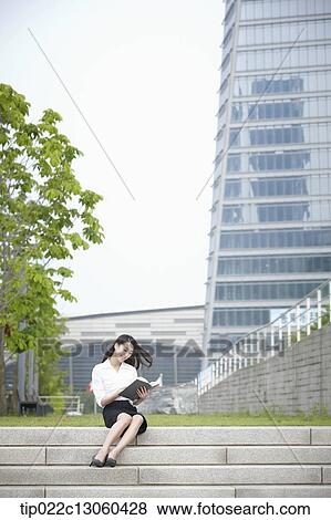Stock Photo - a business woman sitting outside and working. Fotosearch