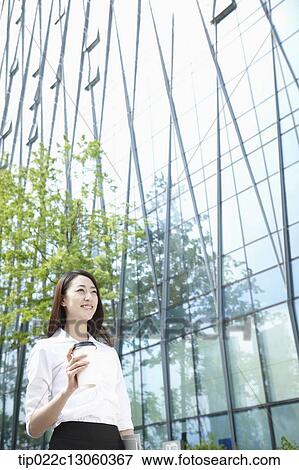Stock Photo - a business woman walking with a coffee. Fotosearch