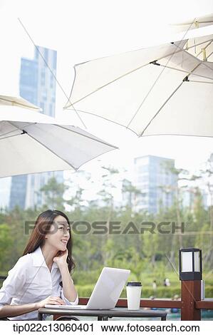 Stock Image - a business woman working while having a coffee. Fotosearch