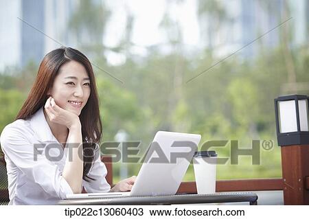 Stock Image - a business woman working while having a coffee. Fotosearch